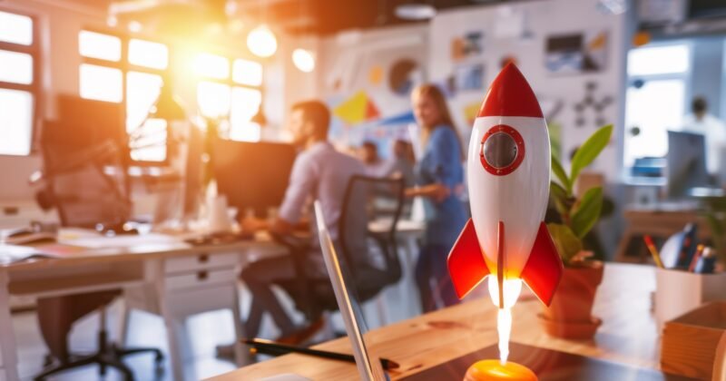 Startup concept. Space rocket from the office desk next to young entrepreneurs, business team